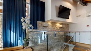 A modern interior with a stone wall, a glass railing, and a mounted TV. - Villa Marta (Split)