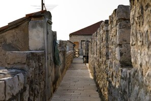 A narrow stone pathway flanked by high stone walls, leading to a building with a tiled roof. - Villa Marta (Split)