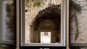 An arched stone doorway leading to a courtyard with a stone wall and a metal railing. - Villa Marta (Split)