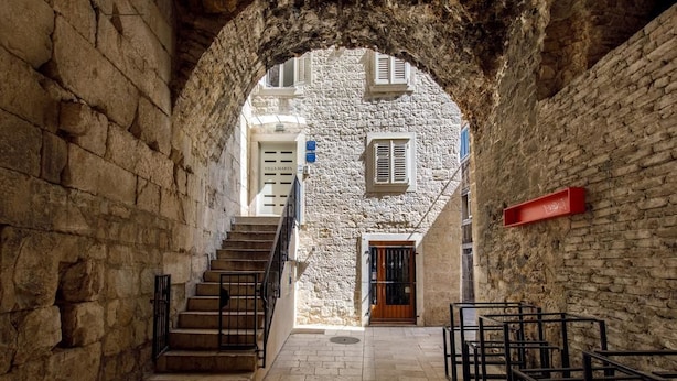 A stone-walled corridor with a staircase leading to a building with a wooden door and a sign that reads "Villa Mare." - Villa Marta (Split)