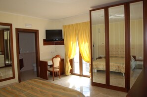 A hotel room with a bed, a desk with a chair, a television mounted above the desk, and a large mirror. - Hotel Insonnia (Agropoli)