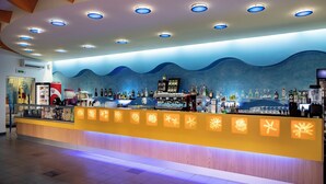 A bar area with a wave-patterned wall, a counter with illuminated icons, and a ceiling with recessed lighting. - Blu Salento Village (Nardò)