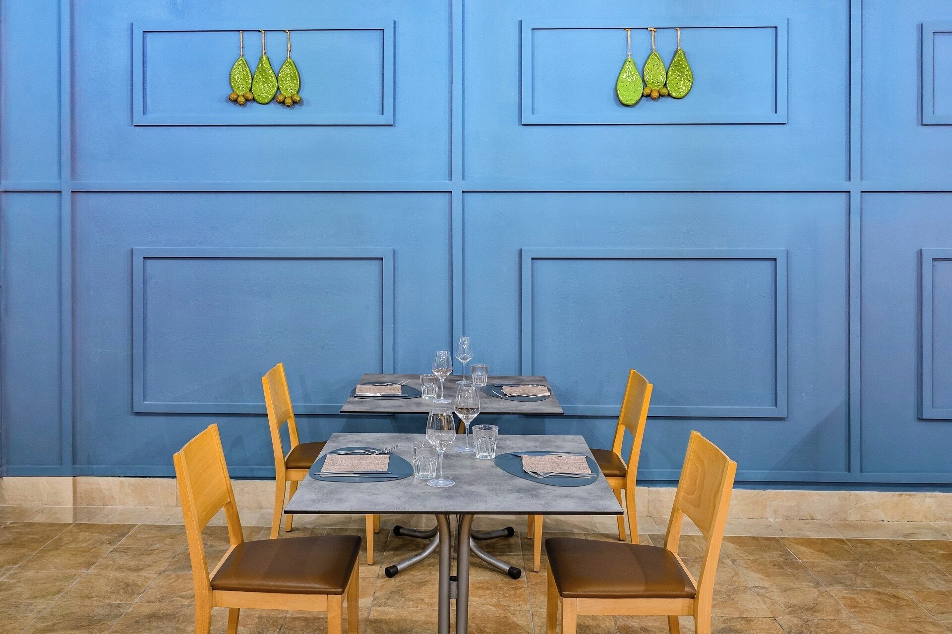 Un comedor con pared azul, una mesa con sillas dispuestas y aretes decorativos en la pared.