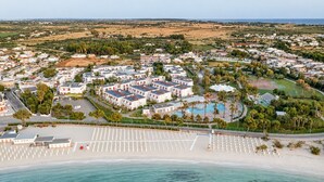 An aerial view of a coastal resort with a swimming pool, beach, and hotel buildings. - Blu Salento Village (Nardò)