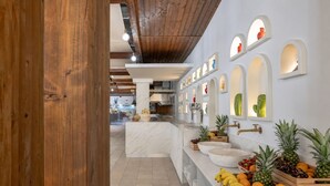 A modern kitchen with marble countertops, wooden beams, and a fruit display. - Blu Salento Village (Nardò)