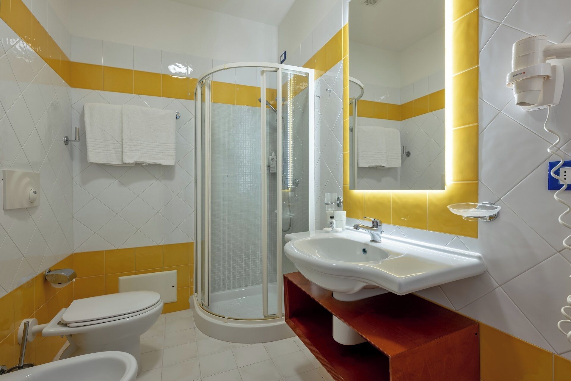 A bathroom with a toilet, bidet, shower, and sink.