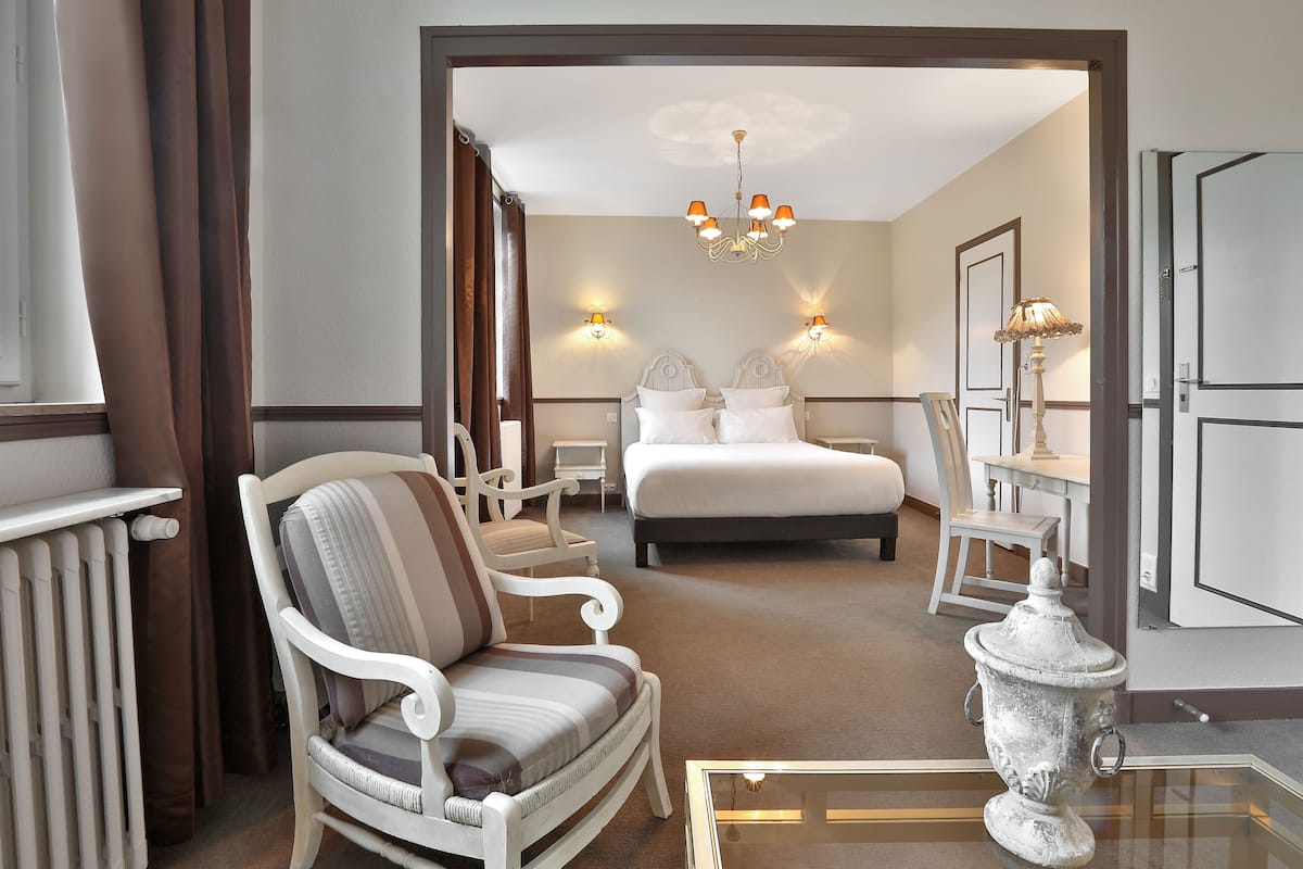 Une chambre d’hôtel comprenant un lit, deux chaises, une table, une lampe et un vase décoratif.