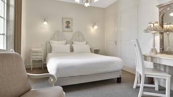 A bedroom with a large bed, two bedside tables, a chair, a desk, and a mirror.