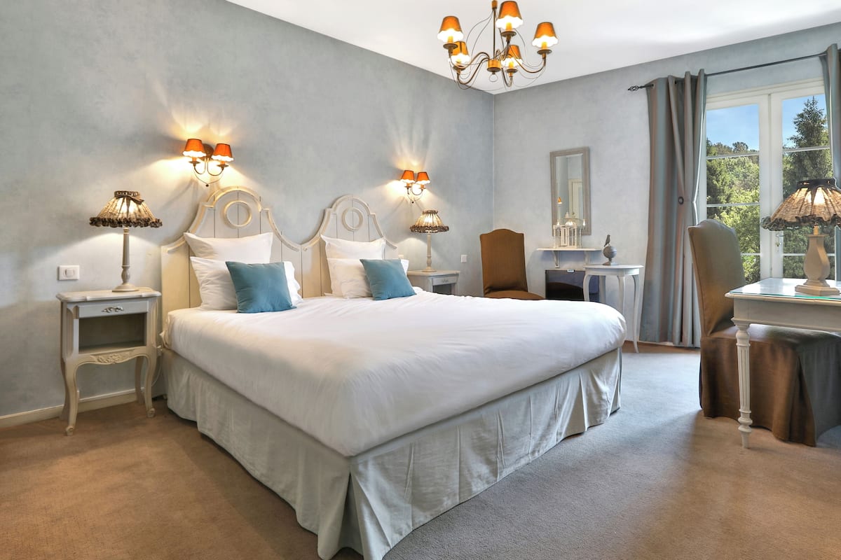 Une chambre spacieuse avec un grand lit, des lampes de chevet, un bureau et une chaise.