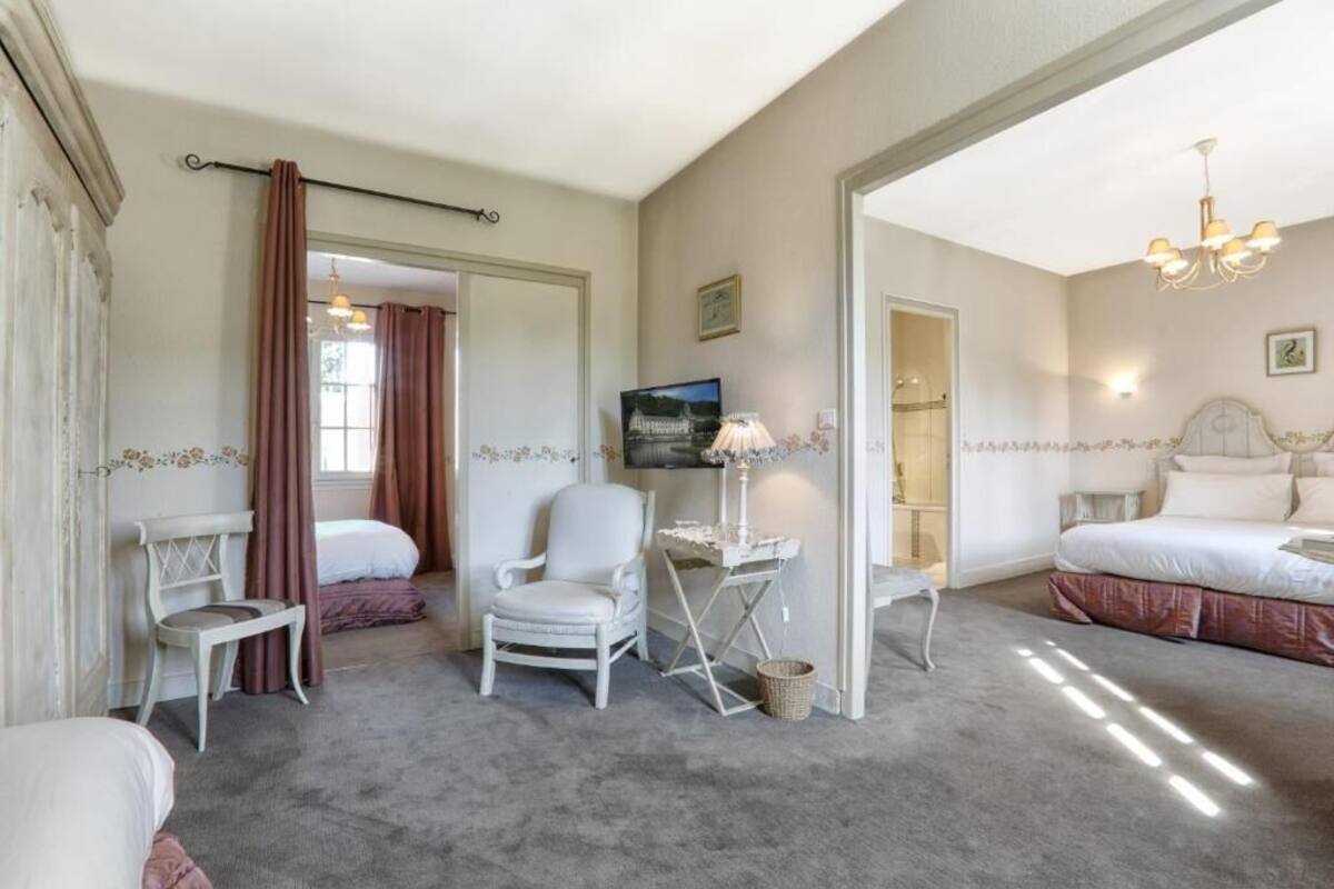 Une chambre d’hôtel avec un grand lit, un bureau avec une lampe, deux chaises et une petite table.