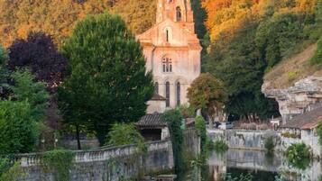 Una iglesia histórica con un campanario, rodeada por un río tranquilo y un bosque denso.