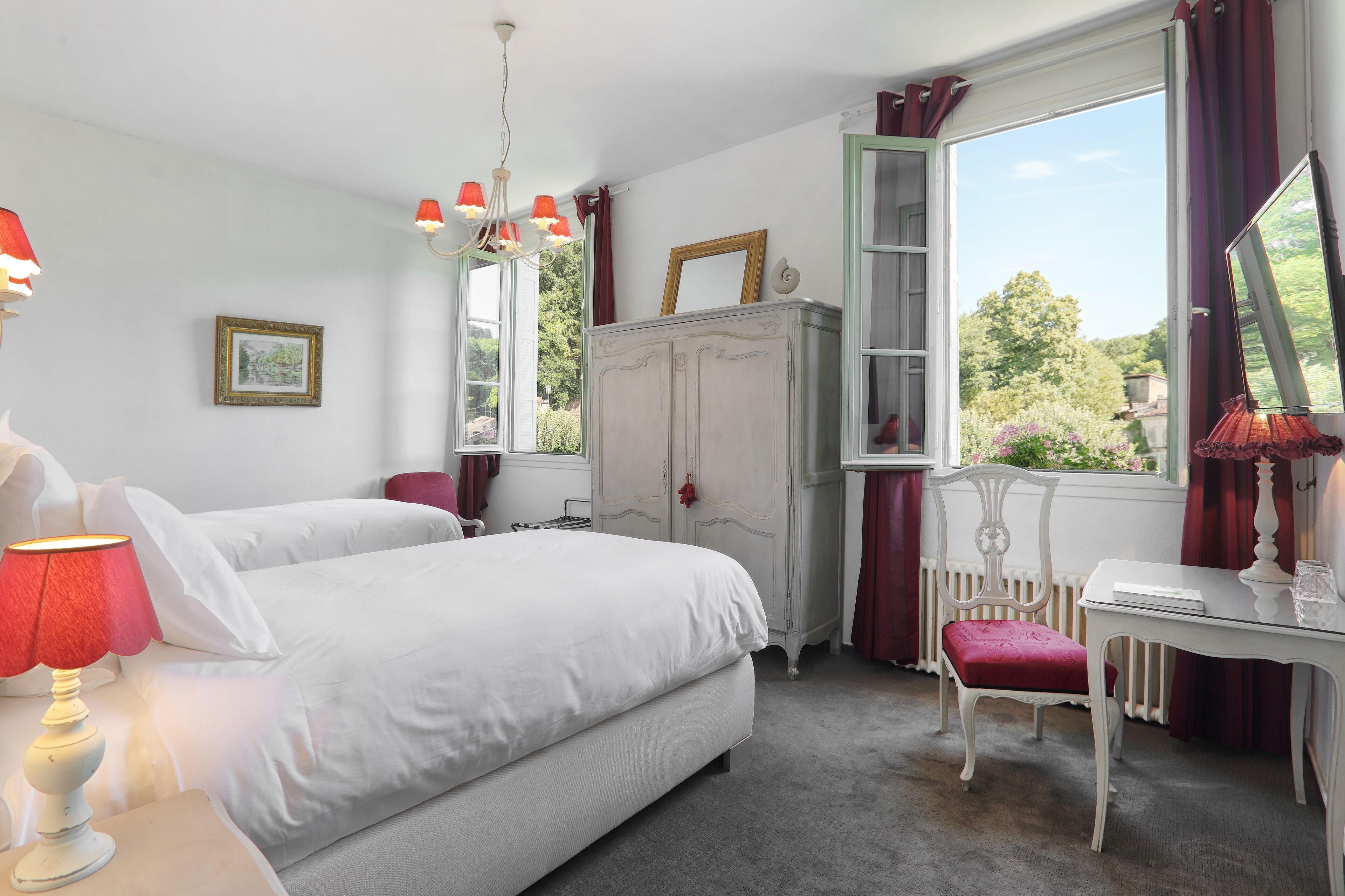 A bedroom with two beds, a dresser, a desk, and a chair.