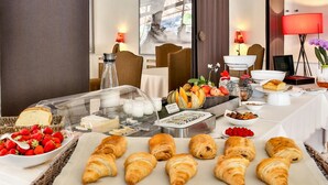 A breakfast buffet with croissants, fruits, and dairy products.