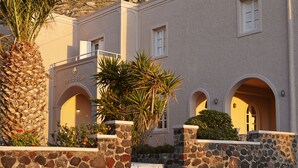 A building with stone walls and arched windows, set against a mountainous backdrop. - Terra Blue Santorini (Santorini)