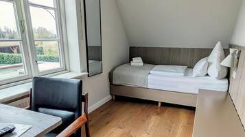 A modern bedroom with a loft bed, a desk with a chair, and a large window.