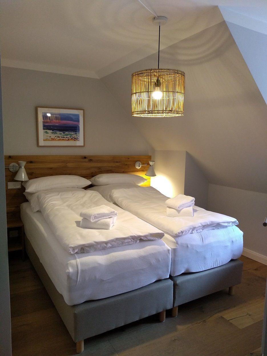 A bedroom with a bed, bedside lamps, and a hanging light fixture.