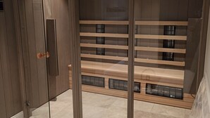 Une salle de bain moderne avec une paroi en verre, un banc en bois et une baignoire.