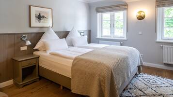 A bedroom with a bed, bedside table, lamp, window, and a framed picture on the wall.