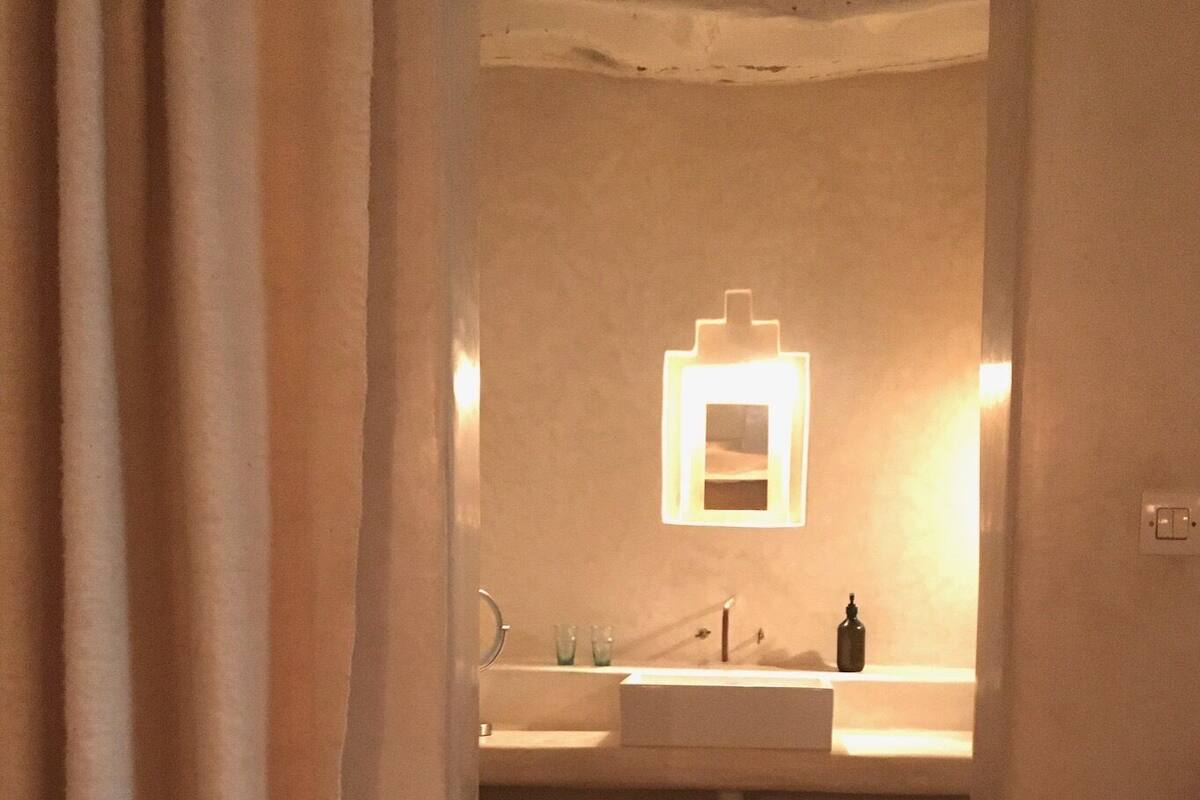 A bathroom with a white sink, a mirror, and a bottle on the counter.