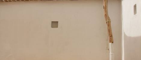 Una habitación con un sofá color beige, un ventanal pequeño y una pared blanca.