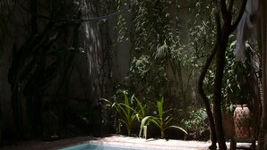 Una piscina rectangular con borde de azulejos, rodeada por un patio de ladrillo.