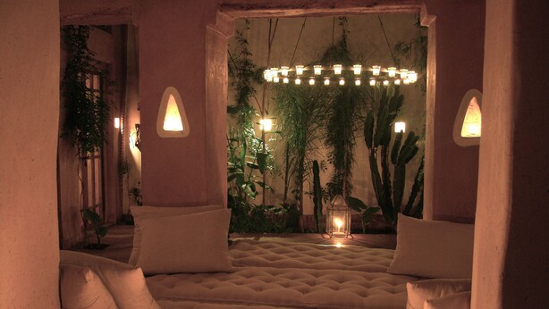 Una habitación acogedora con un sofá capitonado, dos lámparas de pared y una lámpara colgante.