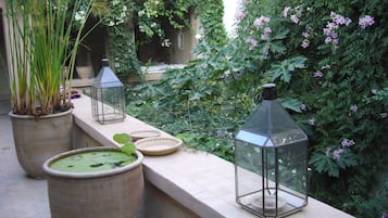 A garden with potted plants and lanterns on a stone ledge.