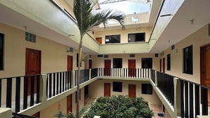 Un atrio de varios niveles con jardín central, balcones y techo de cristal.