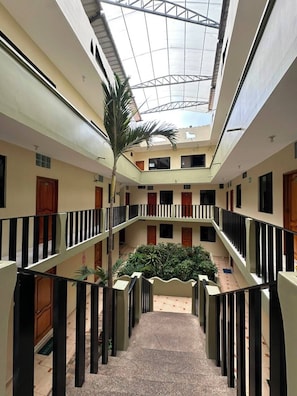 A multi-level atrium with a central garden, balconies, and a glass ceiling. - Grand Hotel Chatham (Puerto Baquerizo Moreno)