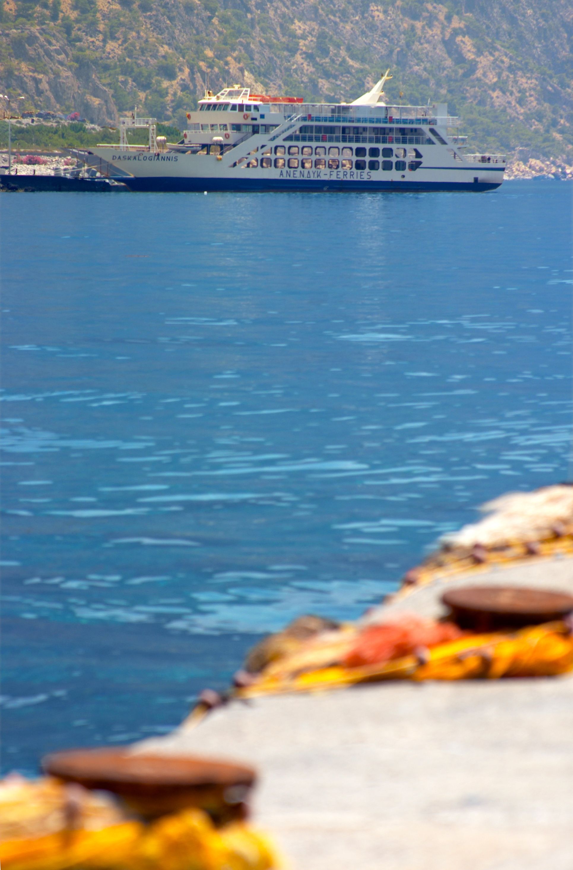 A ferry named "DASKA LOGIANNIS" with a view of rocky cliffs in the background.