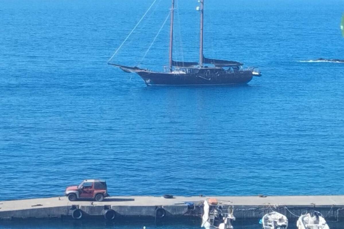 Un bateau était amarré à un quai, et un véhicule rouge se trouvait à proximité.
