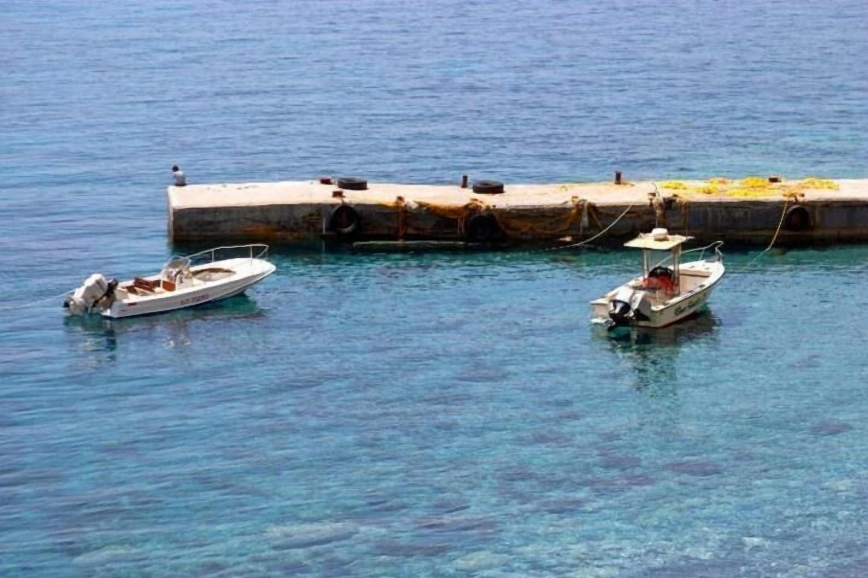 Dos barcos amarrados en un muelle, con agua cristalina.