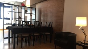 A dining area with a table and chairs, a sideboard with glass doors, and a lamp on a side table. - Sitges Go (Sitges)