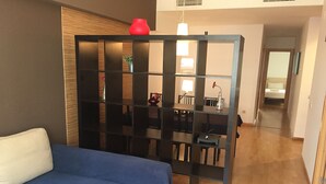 A modern room with a blue sofa, a wooden partition with shelves, and a dining area in the background. - Sitges Go (Sitges)