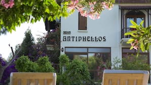 Un edificio con un cartel que dice "ANTIPHELLOS" y un balcón con sillas de madera.