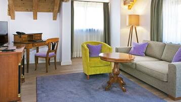 Una sala de estar con un escritorio de madera, un sillón amarillo, un sofá gris y una mesa redonda de madera.