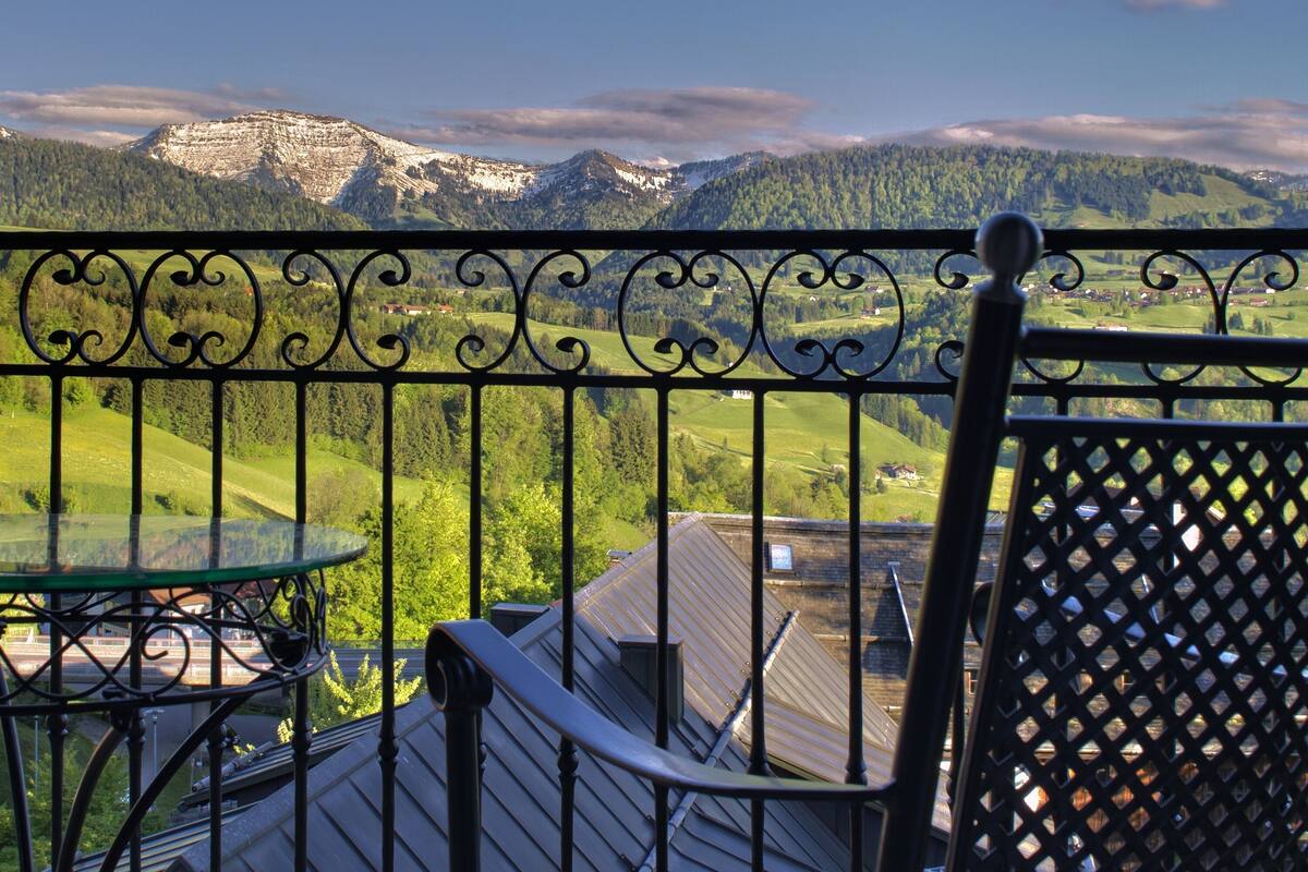 A balcony with a metal railing, a chair, and a table.