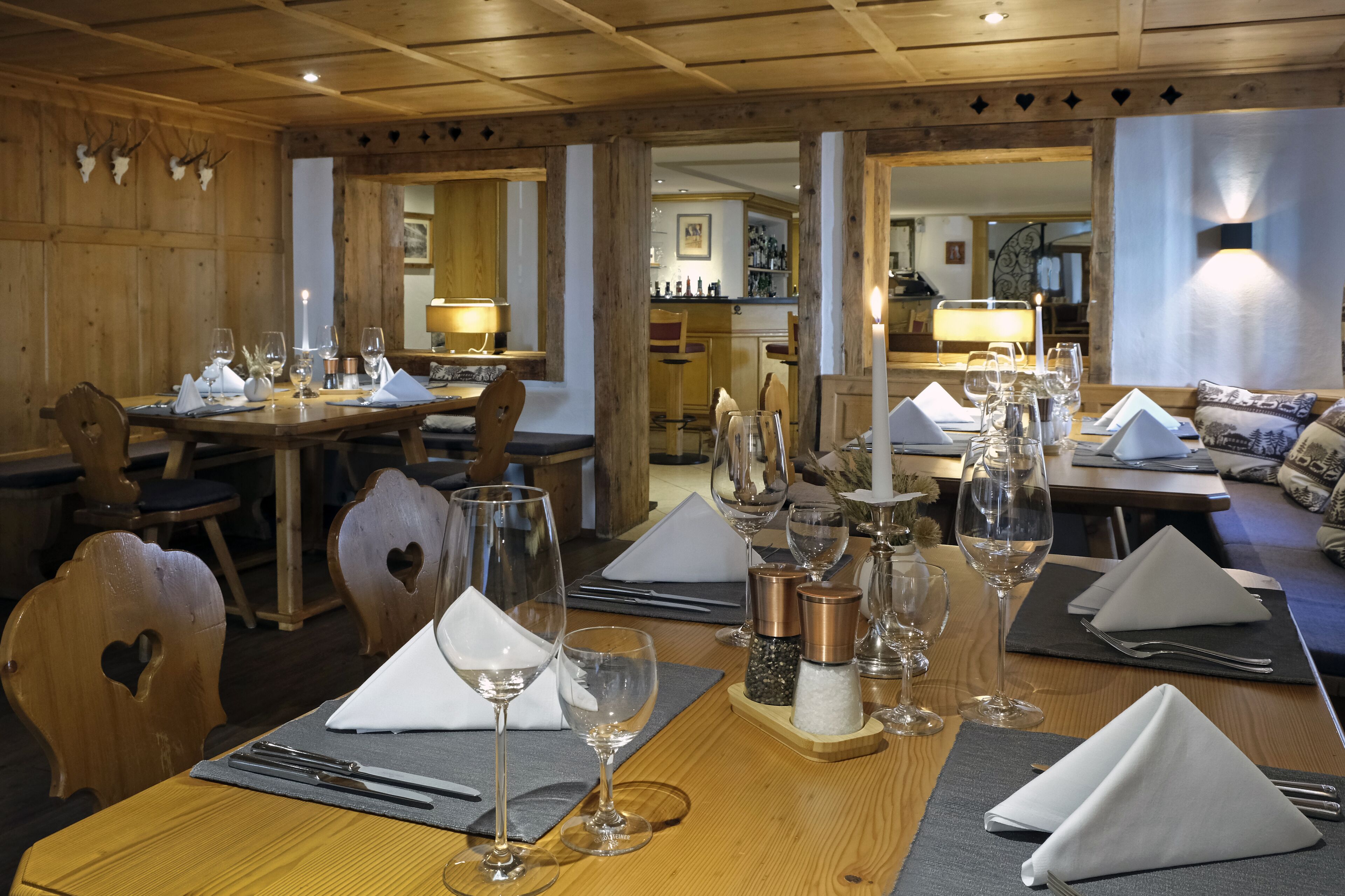 Un restaurant au décor intérieur en bois, avec des tables dressées, nappes blanches, verres à vin et couverts.