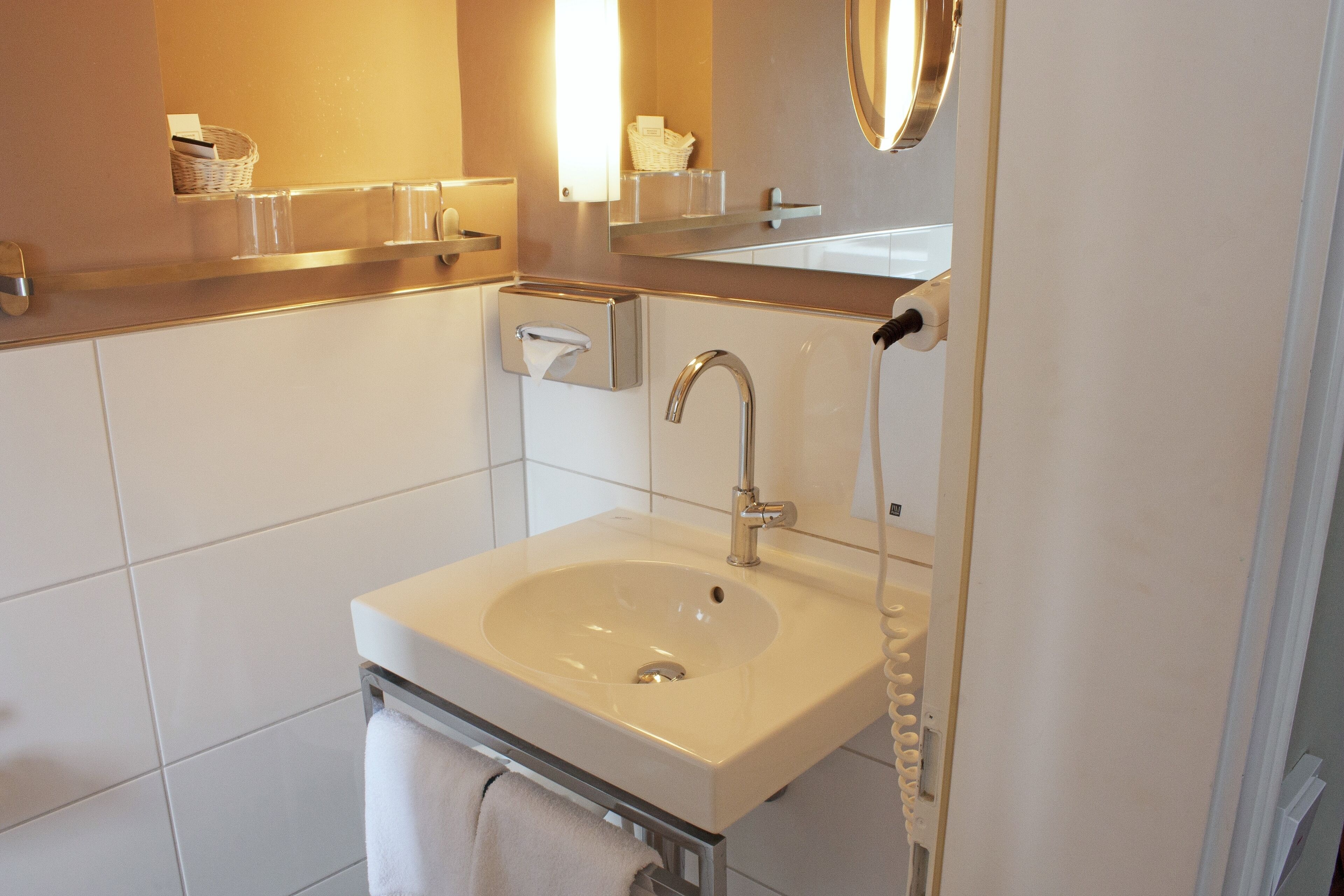 A modern bathroom with a white sink, a mirror, and a towel rack.