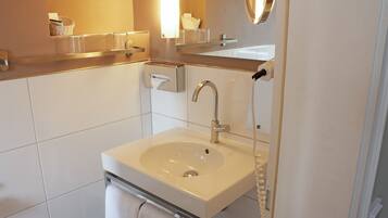 A modern bathroom with a white sink, a mirror, and a towel rack.