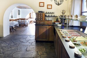 Un restaurante con suelo de baldosas de piedra, armarios de madera y una zona de bufé con diversos alimentos.