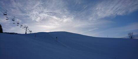 A snow-covered ski slope with a ski lift and a clear sky.