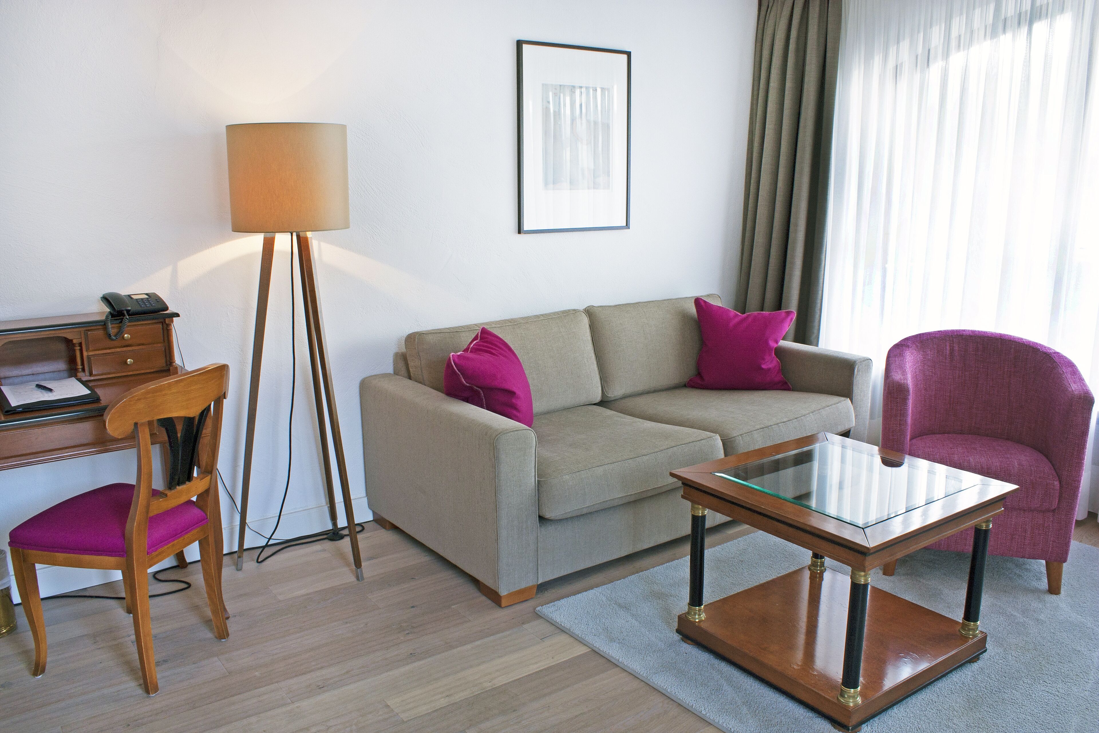A modern living room with a sofa, armchair, and a glass-top coffee table.