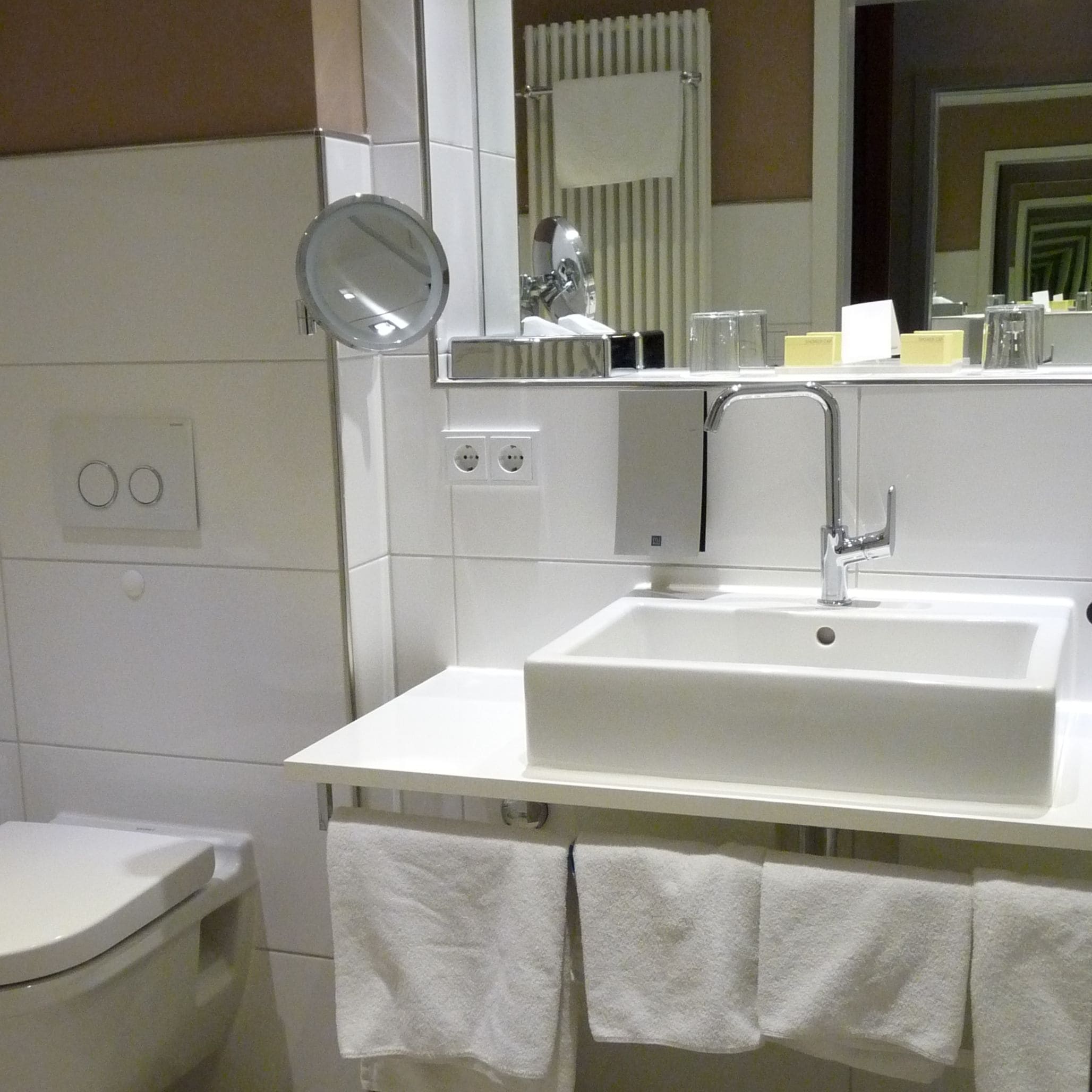 Une salle de bain moderne avec un lavabo blanc, un miroir et un porte-serviettes.