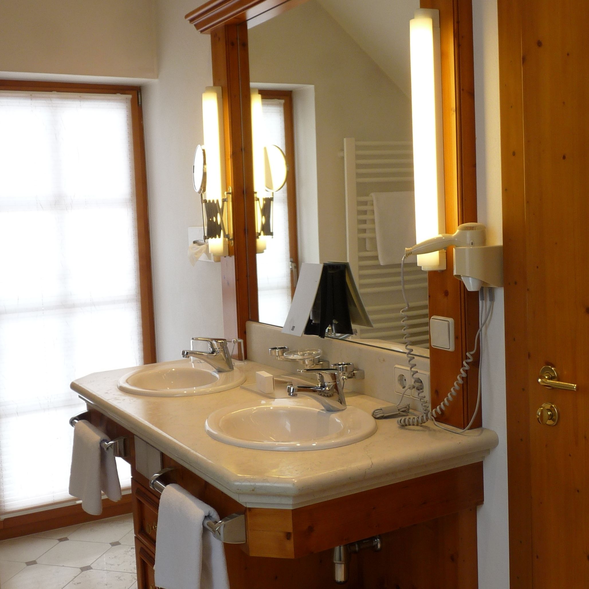A bathroom with two sinks, a large mirror, and a towel rack.