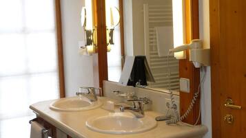 A bathroom with two sinks, a large mirror, and a towel rack.