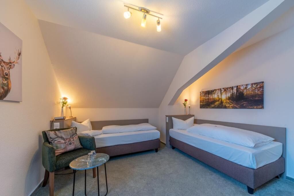 A cozy bedroom with two beds, a small table, and a chair.