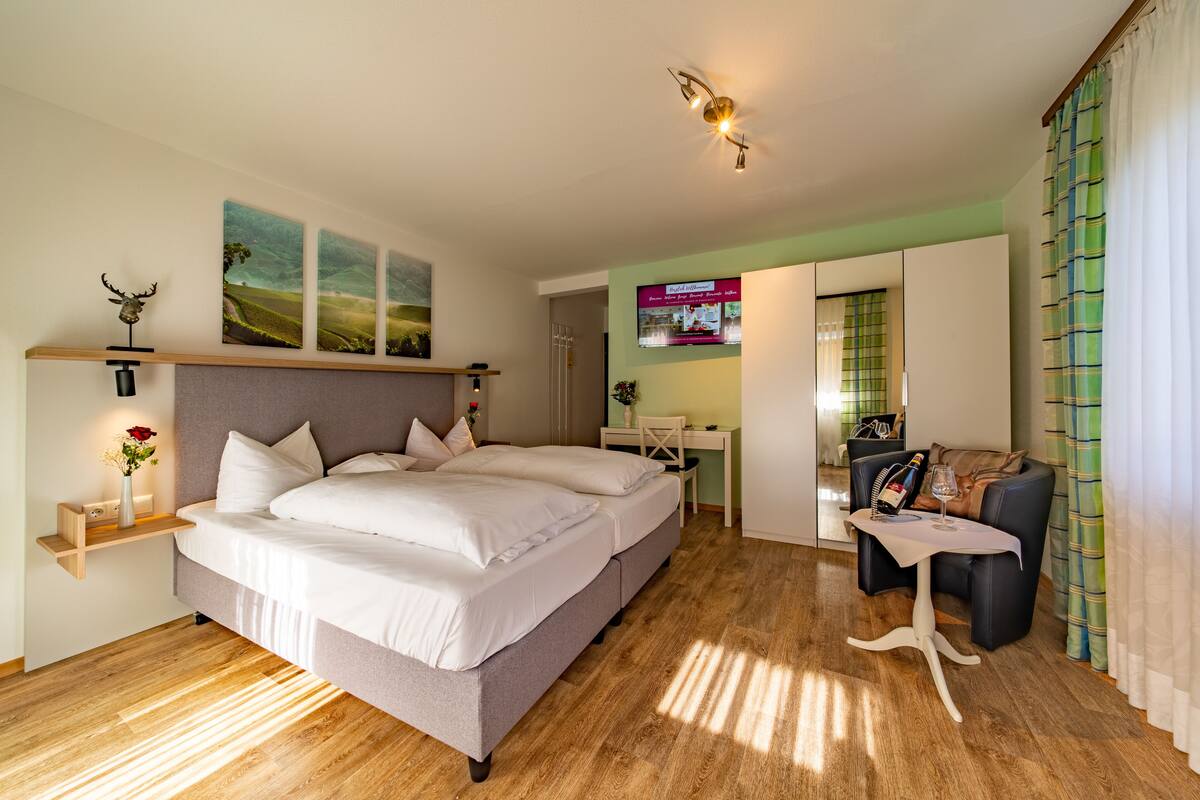 A modern bedroom with a large bed, a desk, and a seating area.