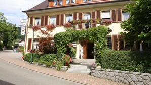 A two-story hotel with a stone facade, wooden shutters, and flower boxes on the windows. - Landhotel Salmen (Oberkirch)