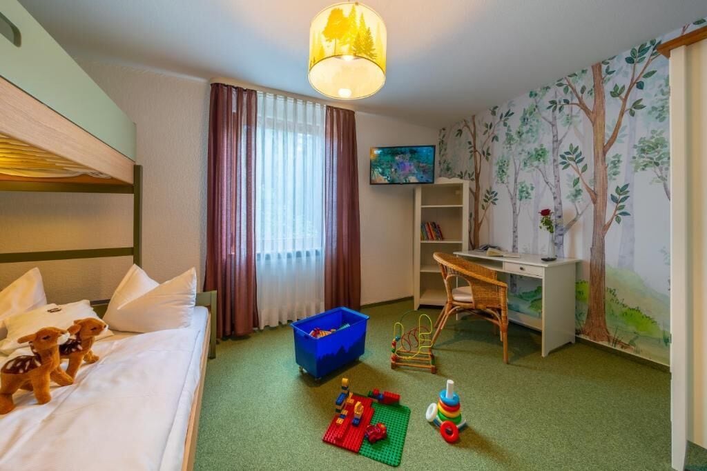 A hotel room with a bed, a desk, a television, and a bookshelf.